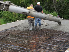 Shown: Two men pouring a concrete garage floor in Erie, PA.